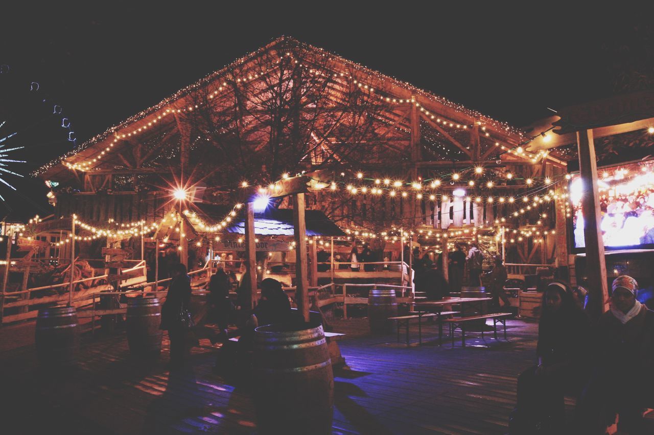 PEOPLE AT ILLUMINATED AMUSEMENT PARK AT NIGHT