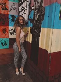 Portrait of woman standing against graffiti wall