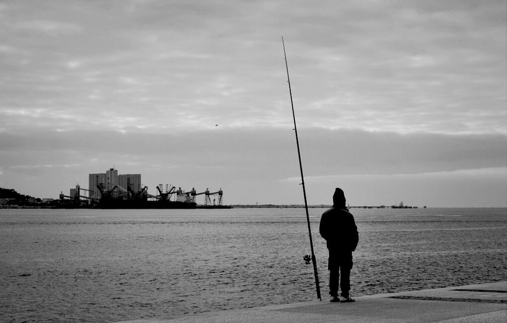 sea, water, sky, men, silhouette, lifestyles, rear view, leisure activity, cloud - sky, full length, standing, beach, person, built structure, horizon over water, nature, tranquility