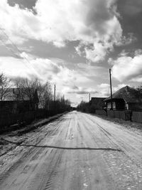 Empty road by buildings against sky