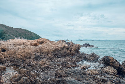 Rock formation on beach against sky