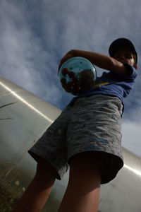 Low angle view of boy playing against sky