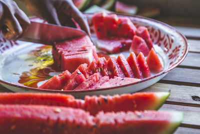 Close-up of man cutting watermelon slices on table