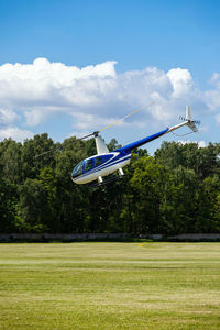 Airplane flying above trees against sky