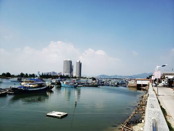 Boats moored in sea against buildings in city