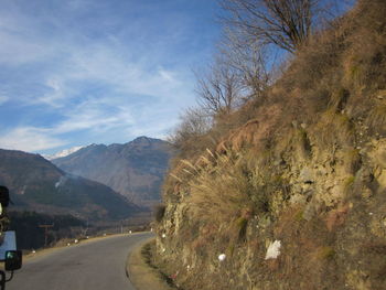 Scenic view of road by mountains against sky