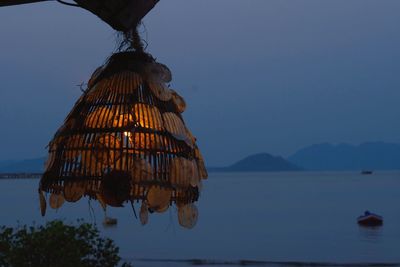 Low angle view of umbrellas hanging by sea against sky