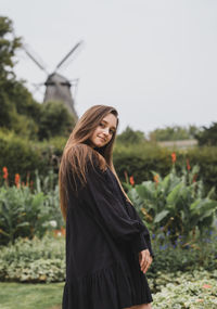 Portrait of smiling young woman standing against sky