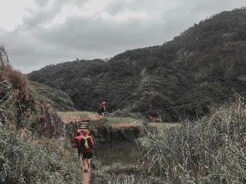 Rear view of men standing on mountain against sky