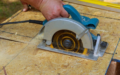 Close-up of man using circular saw on wood