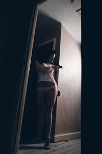 Low angle view of woman aiming gun while standing at home