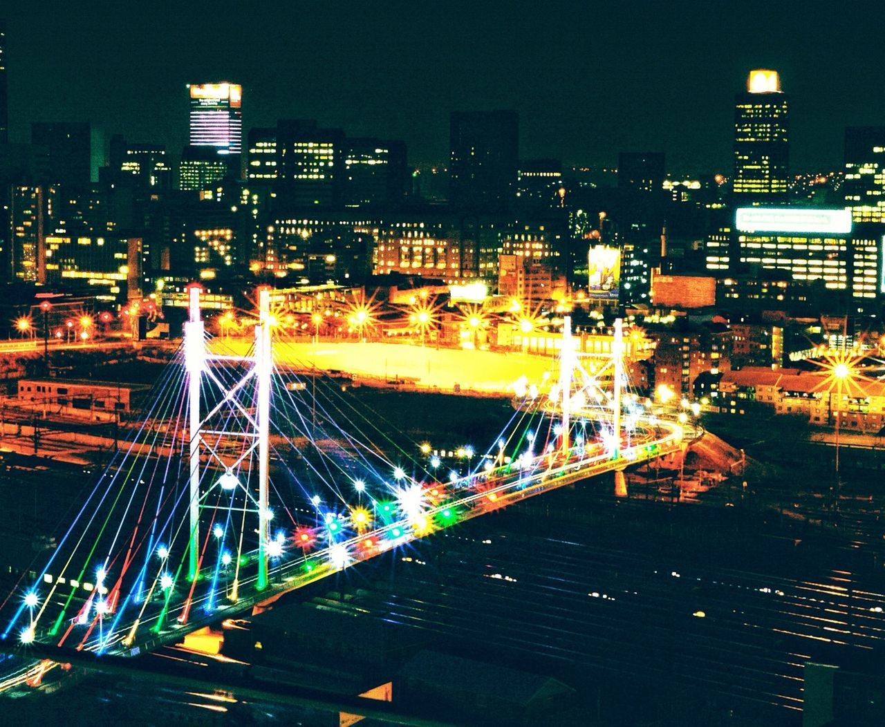 illuminated, night, city, architecture, built structure, building exterior, cityscape, skyscraper, modern, city life, high angle view, capital cities, light trail, tall - high, transportation, office building, bridge - man made structure, long exposure, sky, tower