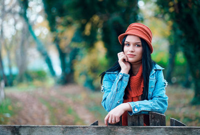 Portrait of beautiful young woman standing against trees