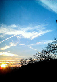 Low angle view of silhouette trees against cloudy sky