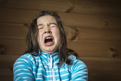 Angry girl shouting against wooden wall