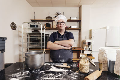 Portrait of confident baker standing with arms crossed in commercial kitchen