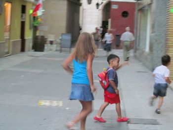 Rear view of women running on street in city