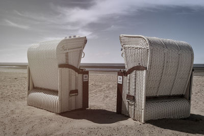 Hooded chairs on beach against sky