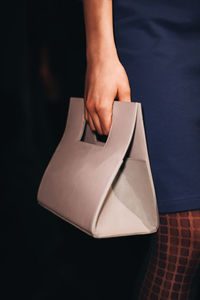 Female hand holding a stylish white minimalist handbag