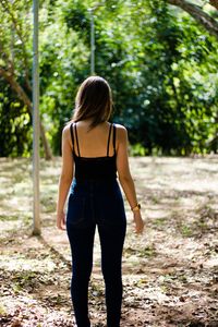 Rear view of teenage girl standing against trees