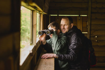 Boy and father birdwatching with binoculars
