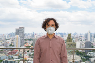 Portrait of man standing against buildings in city