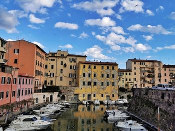 Canal amidst buildings in city against sky