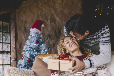 Cheerful couple holding gift box at home