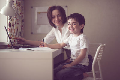 Happy mother is engaged in a laptop with her son preschooler, a real european interior, 