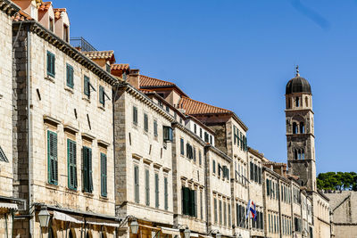 Low angle view of buildings in city against clear blue sky