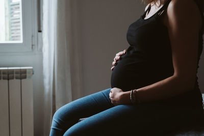 Midsection of pregnant woman resting at home