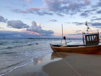 Sailboat moored on sea against sky during sunset