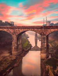 Bridge over river against sky during sunset