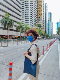 Side view of woman standing on road against buildings
