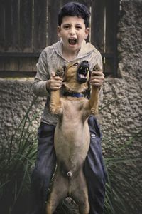 Portrait of boy with dog screaming while standing at yard