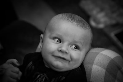 Close-up of smiling baby looking away while lying on sofa at home