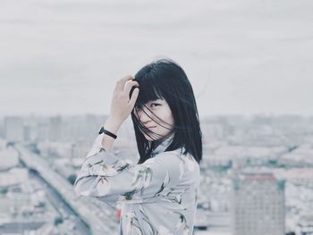 Young woman standing against sky in city