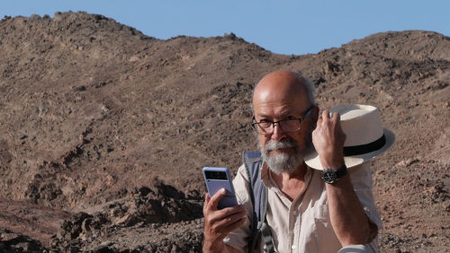 Senior man using smart phone in the desert 