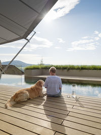 Senior woman sitting with dog at the poolside