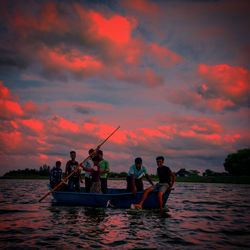 People on boat in sea against sky during sunset