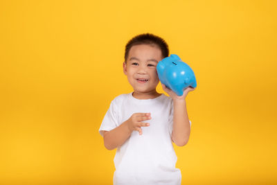 Full length of boy standing against yellow background