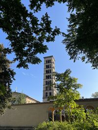 Low angle view of tree by building in city against sky