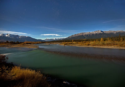 Scenic view of lake by mountains against sky at night