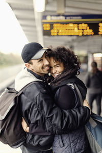 Side view portrait of happy couple embracing on subway platform