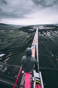 Rear view of man standing by railing against sky