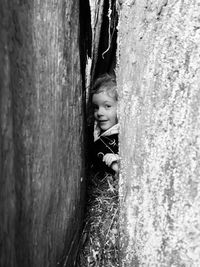 Portrait of cute girl peeking from tree trunk