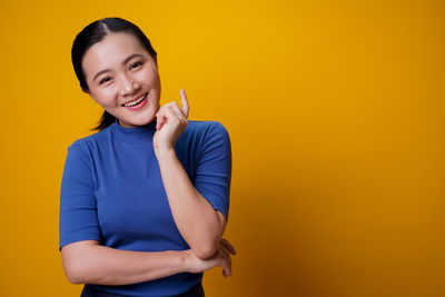 Portrait of smiling man standing against yellow background