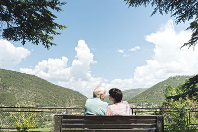 Back view of senior couple sitting on a bench looking at each other, jaca, spain