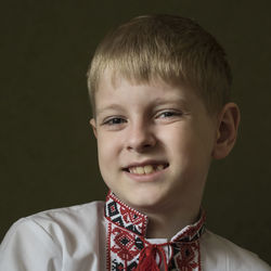 Portrait of smiling boy in traditional clothing against gray background