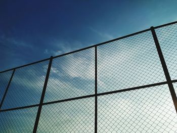 Low angle view of chainlink fence against blue sky